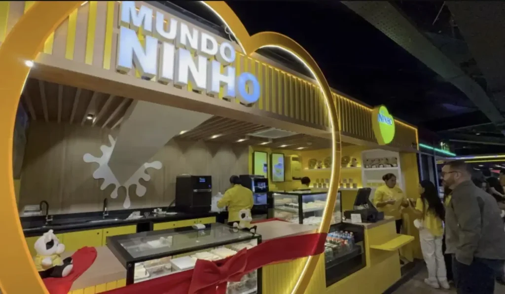 Fachada da loja Mundo Ninho no Terminal 2 do Aeroporto de Guarulhos, com visual amarelo, itens decorativos da marca e vitrines com produtos exclusivos da Nestlé.