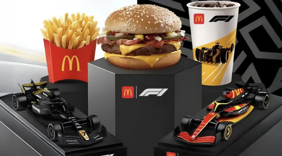 Combo do McDonald's com tema de Fórmula 1, apresentando um hambúrguer, batatas fritas e refrigerante, ladeado por dois carros de corrida de Fórmula 1 em miniatura.