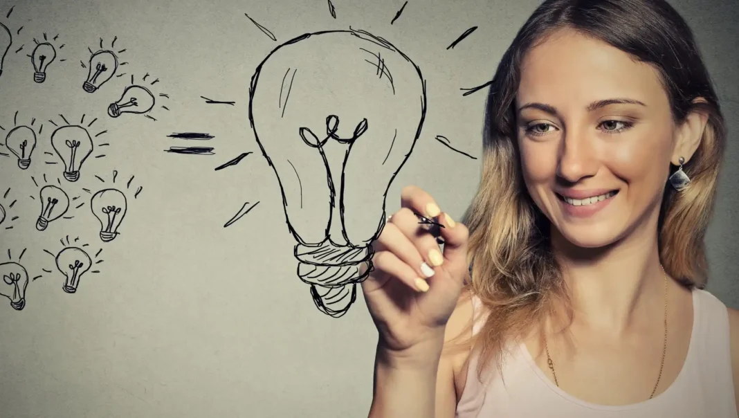 Menina sorridente desenhando várias lâmpadas em um caderno, simbolizando ideias criativas.