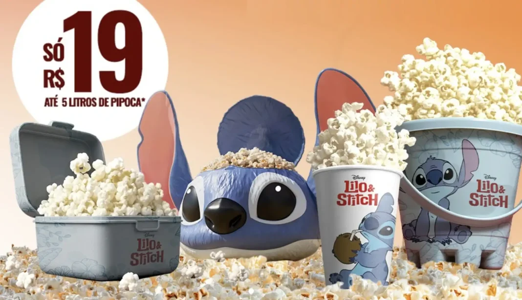 Quatro recipientes de pipoca do Lilo & Stitch, sendo um balde retangular cinza, um balde azul em formato da cabeça do Stitch, um copo com a estampa do Stitch e um balde cilíndrico azul claro. Todos estão cheios de pipoca, sobre uma cama de pipoca.