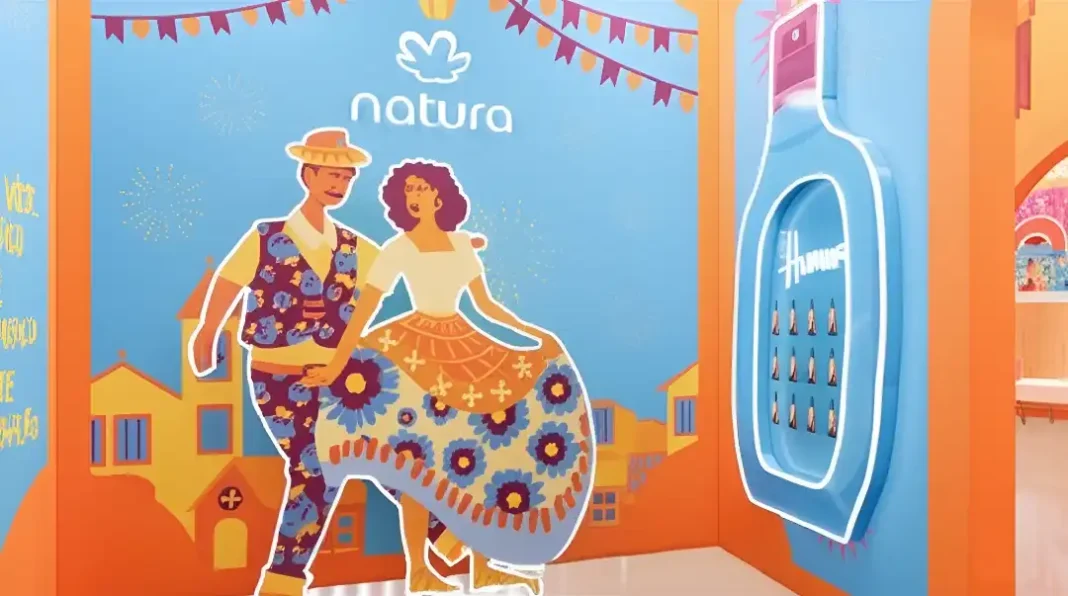 Casal de desenho animado dançando em frente a um painel decorativo com a marca Natura e uma instalação luminosa em formato de frasco de perfume.