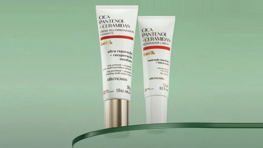 Dois tubos brancos de produtos Botik Cica Pantenol + Ceramidas, um creme multirreparador calmante e um reparador labial, exibidos em uma prateleira de vidro.