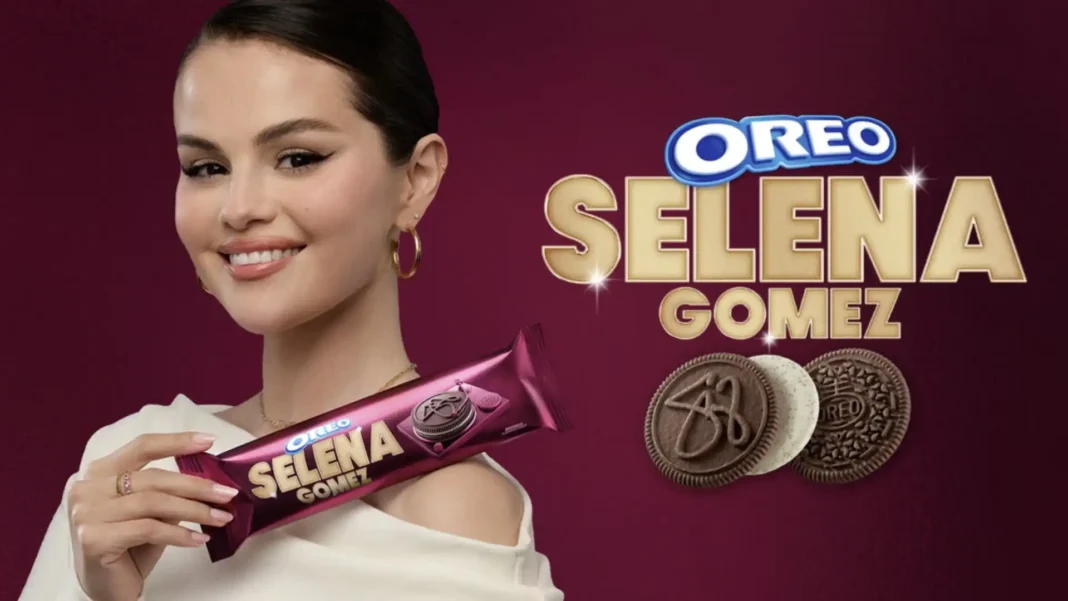 Selena Gomez sorrindo e segurando um pacote roxo de biscoitos Oreo Selena Gomez, com a marca Oreo Selena Gomez e três biscoitos Oreo de diferentes sabores ao lado.