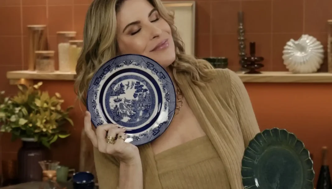 Rita Lobo sorrindo enquanto segura um conjunto de pratos da Oxford em ambiente de cozinha.