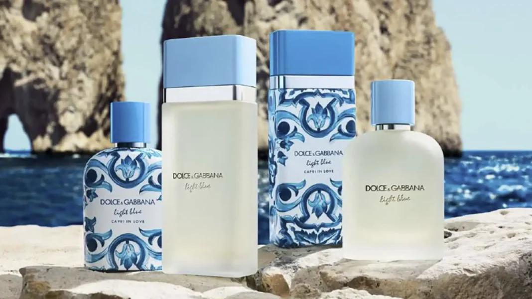 Quatro frascos de perfume Dolce & Gabbana Light Blue em um cenário costeiro ensolarado.