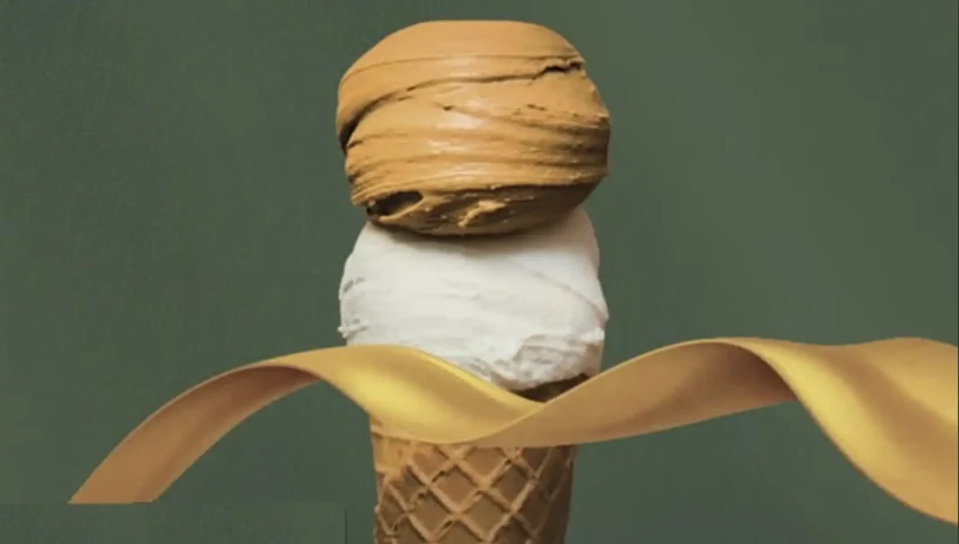 Casquinha de sorvete com duas bolas, a de baixo branca e a de cima marrom, ambas envoltas por um laço dourado esvoaçante.