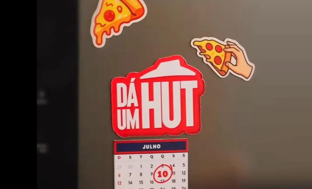 Ímãs de geladeira da Pizza Hut, incluindo um calendário de julho de 2025 com o dia 10 circulado, em uma geladeira.