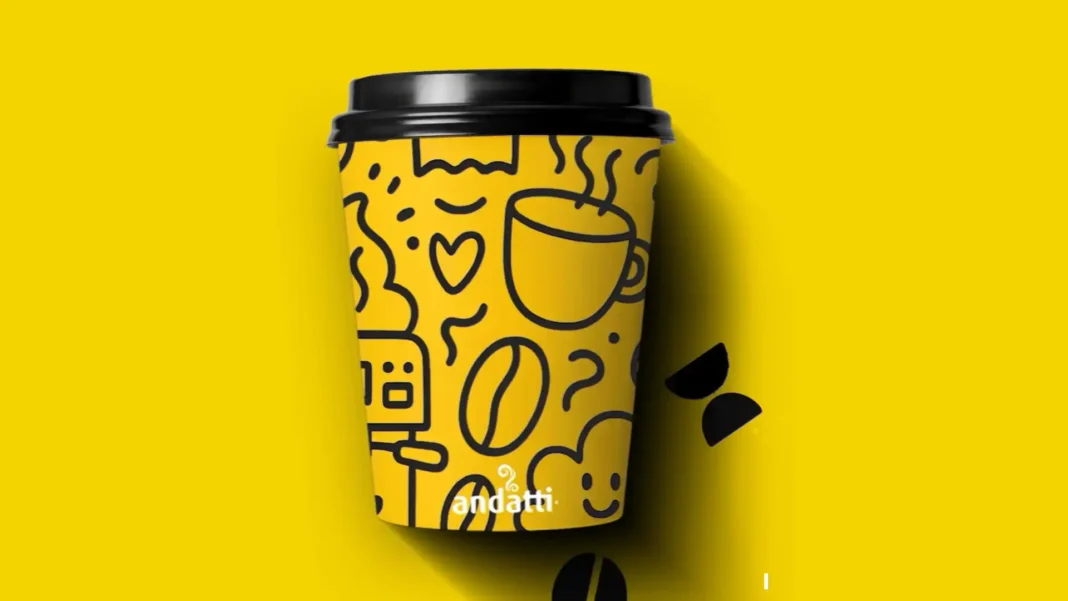 Copo de café Andatti amarelo com ilustrações em preto e tampa preta.