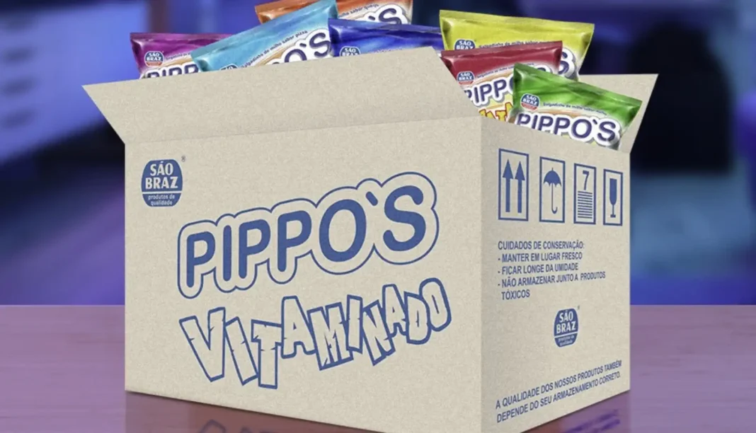 Caixa de papelão aberta e cheia de pacotes coloridos de salgadinhos Pippo's Vitaminado, com o logo da marca São Braz visível.
