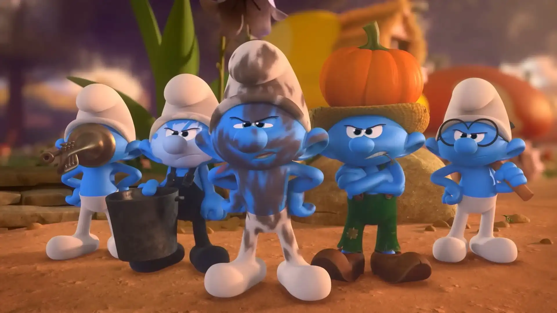 Cinco Smurfs com expressões zangadas estão de pé lado a lado. O do centro está coberto de lama, um à direita usa um chapéu de palha com uma abóbora e um à esquerda segura um balde.