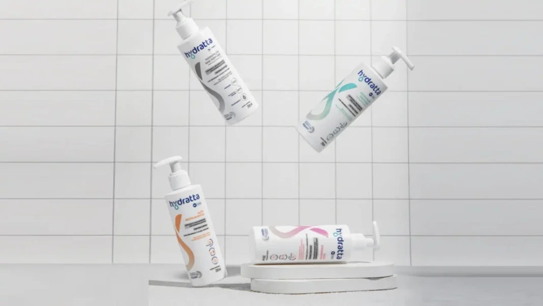 Quatro produtos da marca Hydratta, parecendo ser shampoos ou condicionadores, flutuando ou posicionados em um cenário minimalista com azulejos brancos.