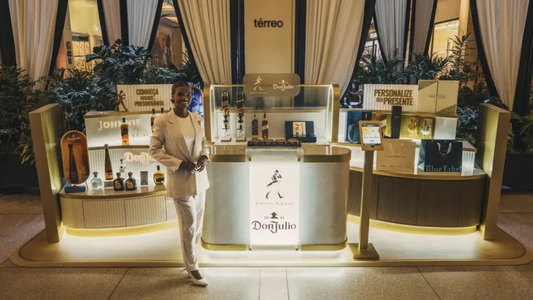 Mulher sorridente em estande de degustação e personalização de uísque Johnnie Walker e tequila Don Julio.