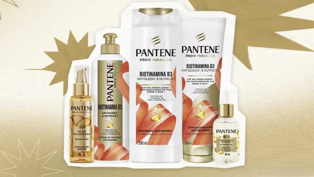 Um banner de publicidade para a linha Pantene Pro-V Miracles, mostrando cinco produtos dispostos em uma formação irregular sobre um fundo claro com estrelas douradas. Da esquerda para a direita, há um pequeno frasco de 'Óleo Milagroso' com aplicador em spray, um frasco maior de 'Creme de Pentear Antiqueda', um frasco de 'Shampoo Antiqueda' de 300 ml, um frasco de 'Condicionador Antiqueda' de 170 ml e um pequeno frasco de 'Tônico Antiqueda'