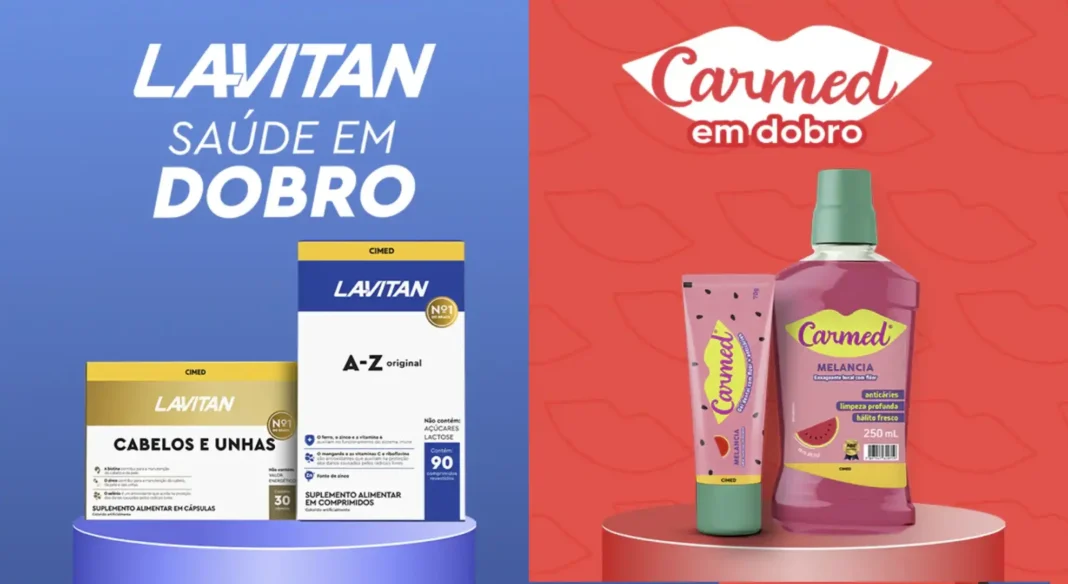Dois pedestais, um azul e um vermelho. No azul, produtos Lavitan: caixas de 'Cabelos e Unhas' e 'A-Z original' com 'Lavitan Saúde em Dobro'. No vermelho, produtos Carmed: um hidratante labial e um enxaguante bucal de melancia com 'Carmed em Dobro'.