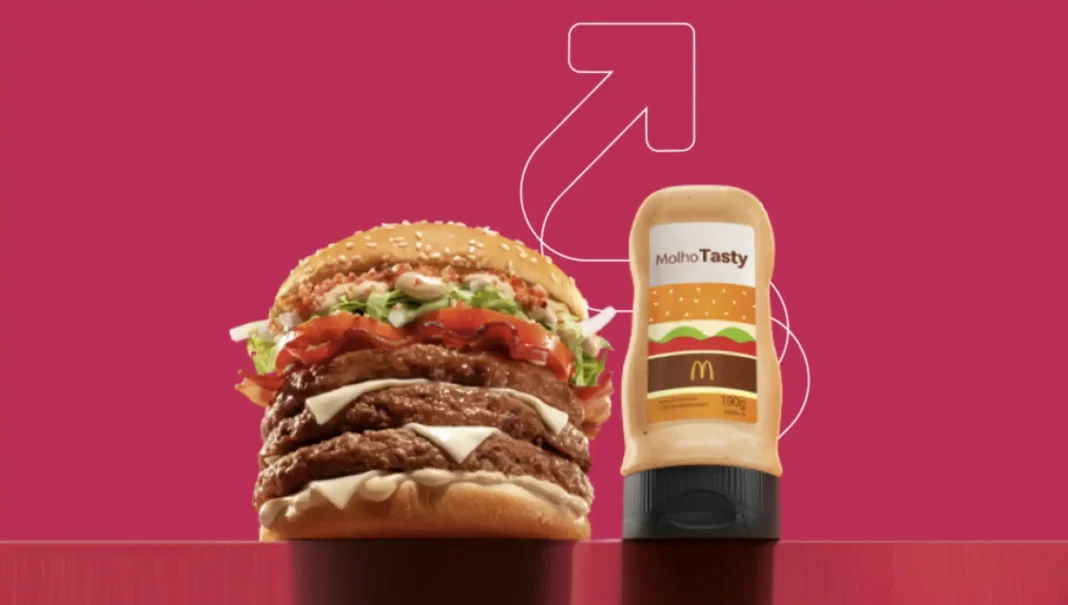 Hamburguer com duas carnes e bacon ao lado de uma embalagem de molho Tasty do McDonald's.