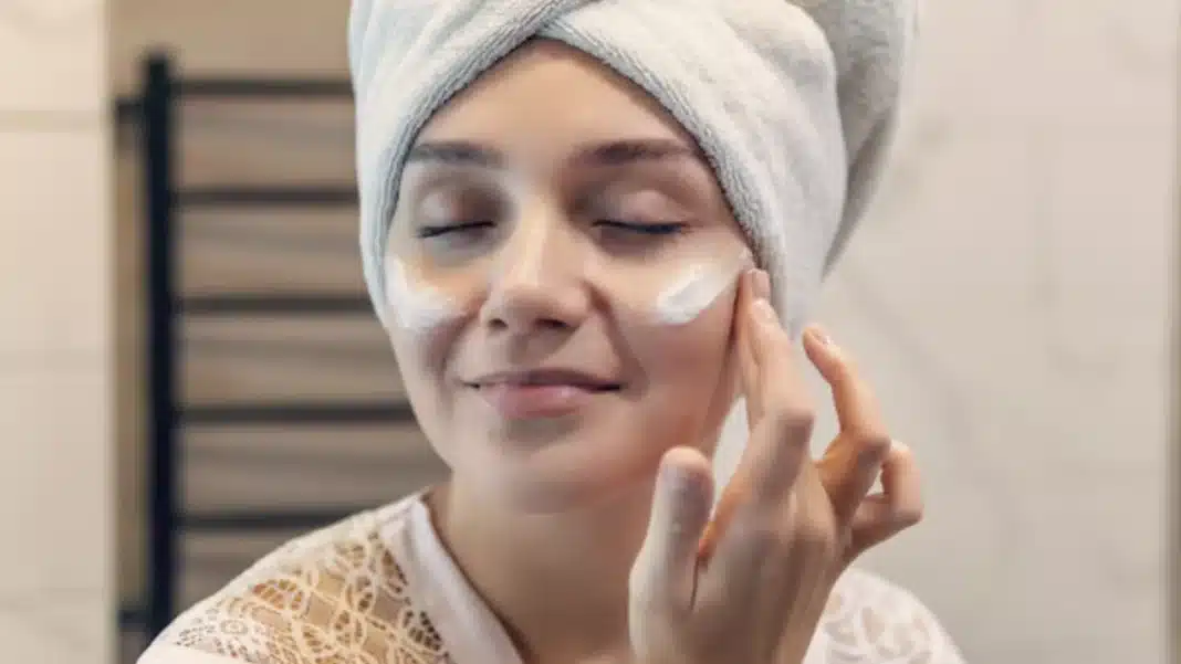 Um close-up de uma mulher em um roupão de seda, com uma toalha enrolada em sua cabeça.