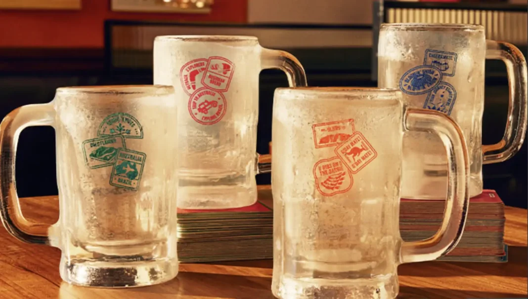 Quatro canecas de chope do Outback, em diferentes tamanhos, estão vazias em cima de uma mesa.