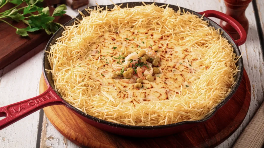 Prato de camarão com massa de macarrão frito em uma panela vermelha.