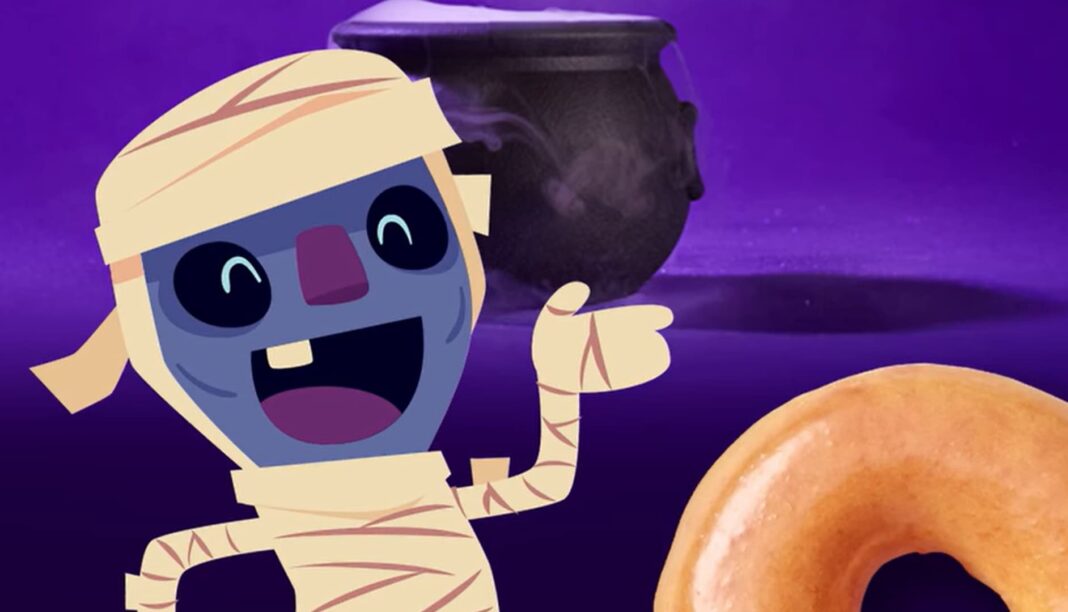 Krispy Kreme oferece donut grátis para quem for fantasiado no Halloween Desenho de múmia sorrindo com um donut e um caldeirão.