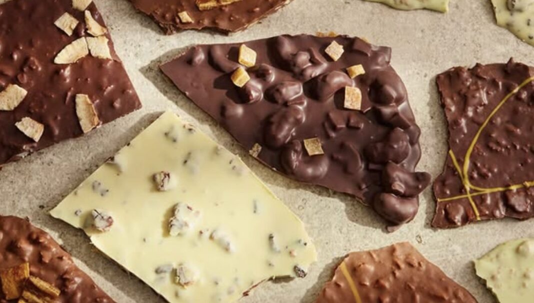 Lascas de chocolate artesanal variadas com toppings de castanhas e frutas.