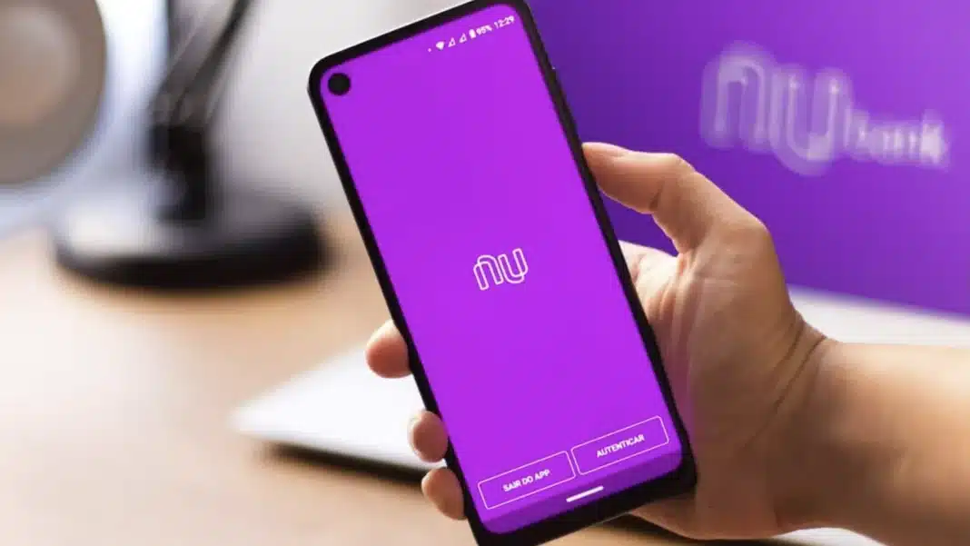 Um celular na mão de uma pessoa, com o aplicativo do Nubank aberto, exibindo a tela roxa de login.