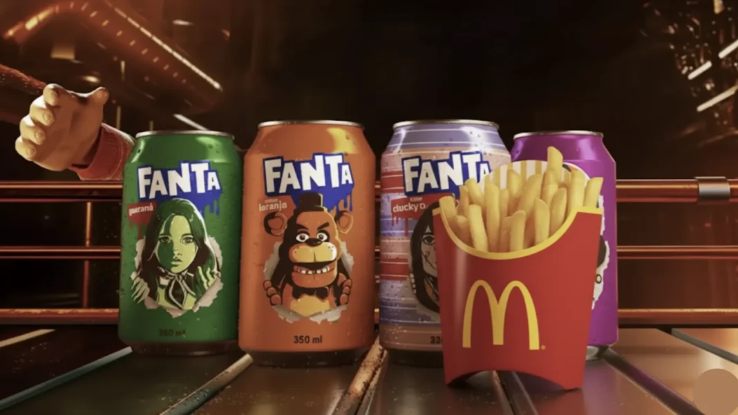 Três latas temáticas de Fanta Halloween (verde Guaraná, laranja Laranja, roxa Chucky) ao lado de uma porção de McFritas em um copo de papelão vermelho do McDonald's.